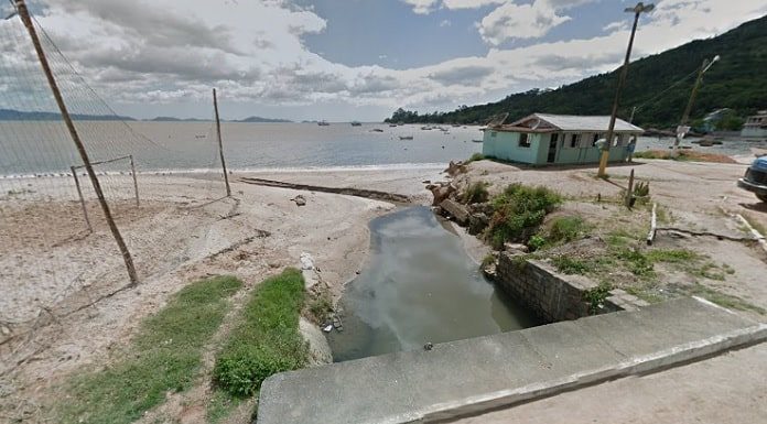 riacho na praia com quadra de areia ao lado e casebre de madeira