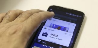 mão sobre um smartphone com logo do enem na tela