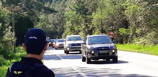 policial no ascostamento de rodovia no meio da mata observa carros passando