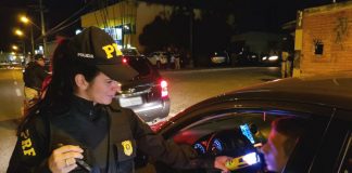 policial aplica teste de bafômetro passivo com luz verde em motorista dentro de carro na marginal da br