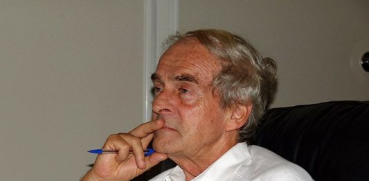 belmiro visto de lado com a mão no rosto segurando uma caneta e contemplativo