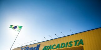 fachada de uma loja com inscrição brasil atacadista e bandeira do brasil em mastro ao lado na frente do sol