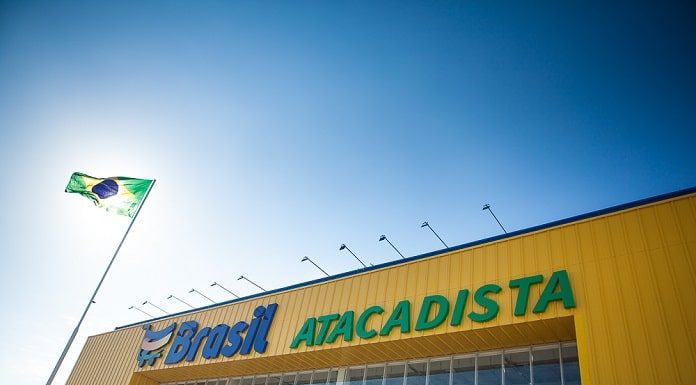 fachada de uma loja com inscrição brasil atacadista e bandeira do brasil em mastro ao lado na frente do sol