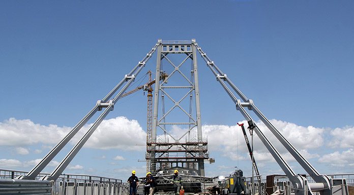 foto do chão gradeado da ponte, da torre e de das barras de olhas que sustentam a estrutura dos lados