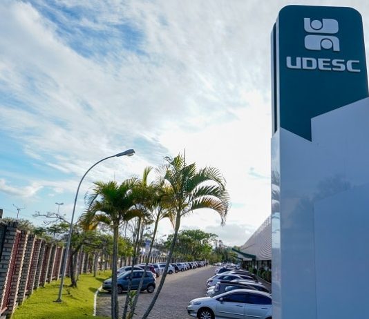 Udesc divulga lista de aprovados no Vestibular de Verão torre com inscrição da udesc no topo ao lado de prédio e estacionamento do campus