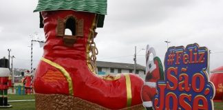 decoração em gramado com uma bota de papai noel gigante e um painel inscrito #felizsãojosé