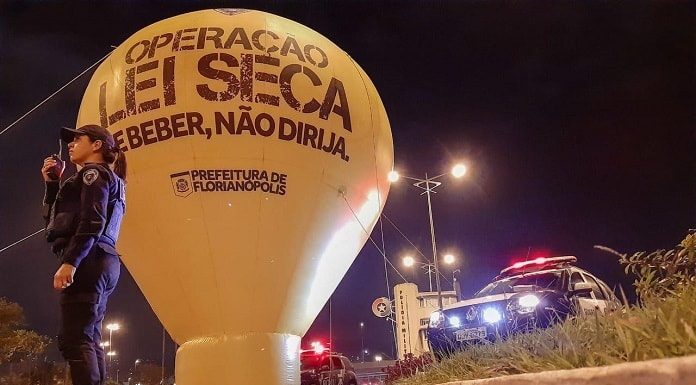 balão inflável da operação lei seca em via pública com uma agente da guarda ao lado e viatura na cabeceira da ponte