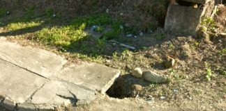 buraco ao lado de uma calçada, parte de cimento, parte de terra