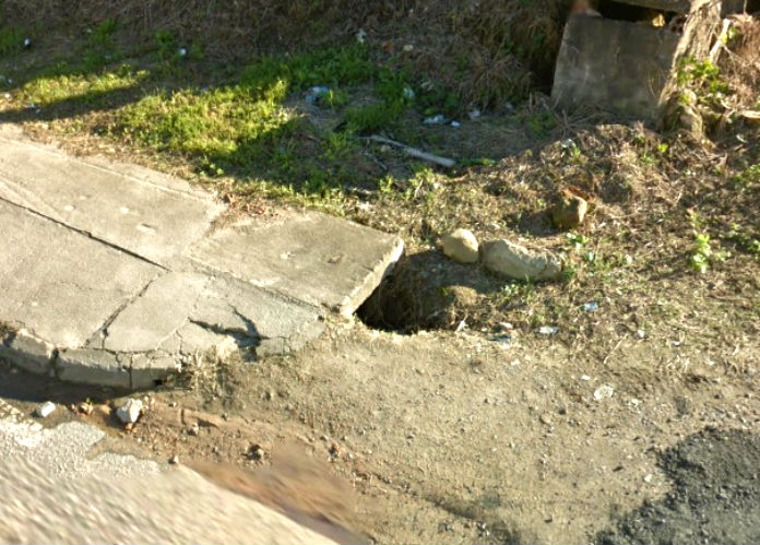 buraco rua-min buraco ao lado de uma calçada, parte de cimento, parte de terra