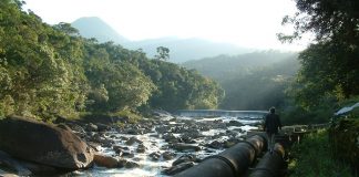 canos de adutora ao lado do rio cubatão em meio à vegetação