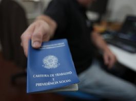 homem aponta para a câmera uma carteira de trabalho e previdência social