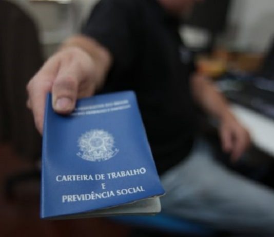 Taxa de desemprego em SC é de 5,8%, cerca de 222 mil pessoas homem aponta para a câmera uma carteira de trabalho e previdência social