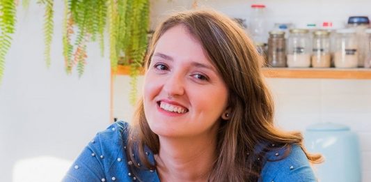 cristal sorri para câmera em uma cozinha com utensílios na parede ao fundo