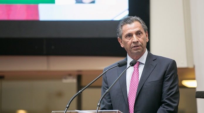 julio garcia de terno discursando na tribuna da alesc com telão ao fundo