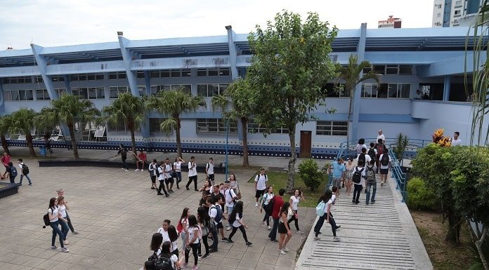 foto do prédio e do pátio do instituto estadual de educação com alunos em uma fila