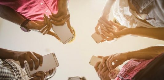 cinco pessoas em roda usando celulares vistas de baixo