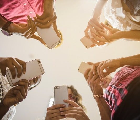 cinco pessoas em roda usando celulares vistas de baixo