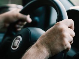 close em mãos masculinas segurando volante com logo da marca fiat