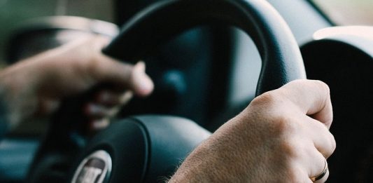 close em mãos masculinas segurando volante com logo da marca fiat
