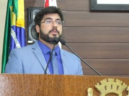 vereador maikon costa discursa na tribuna da câmara de florianópolis com bandeira atrás