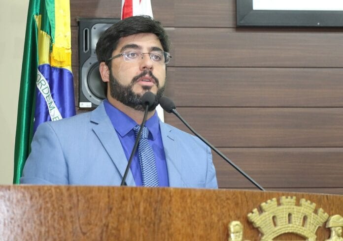 vereador maikon costa discursa na tribuna da câmara de florianópolis com bandeira atrás