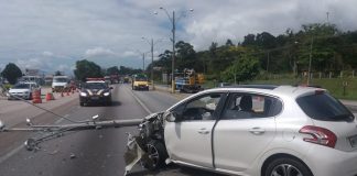 peugeot 206 batido na parte frontal esquerda no meio da rodovia com poste caído à frente