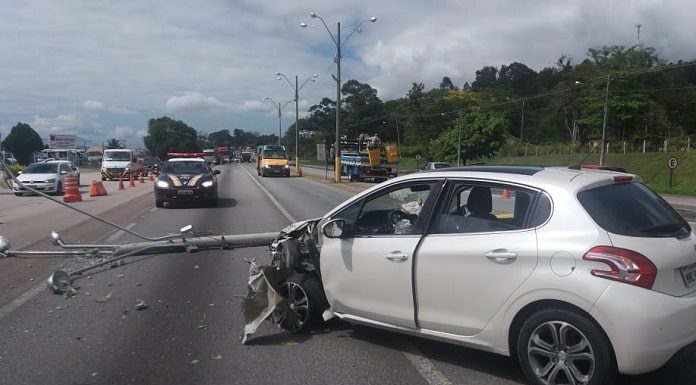 peugeot 206 batido na parte frontal esquerda no meio da rodovia com poste caído à frente