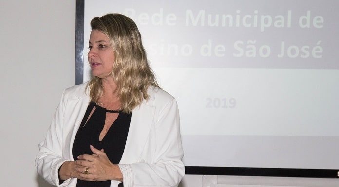 lilian em pé discursando com uma projeção de slide atrás