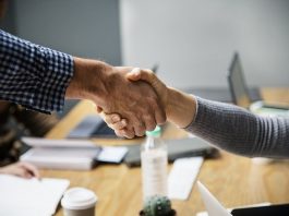 Semana nacional da conciliação terá edição virtual para resolver conflitos e dívidas close nas mãos de um homem e uma mulher se cumprimentando, com mesa de escritório ao fundo