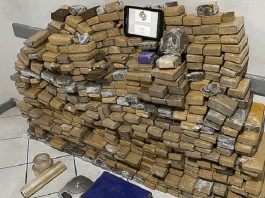 pilha de pacotes no chão com tablet com logo da pm por cima