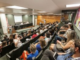 auditório da alesc lotado e com pessoas em bancada em palco à frente