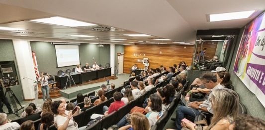 auditório da alesc lotado e com pessoas em bancada em palco à frente