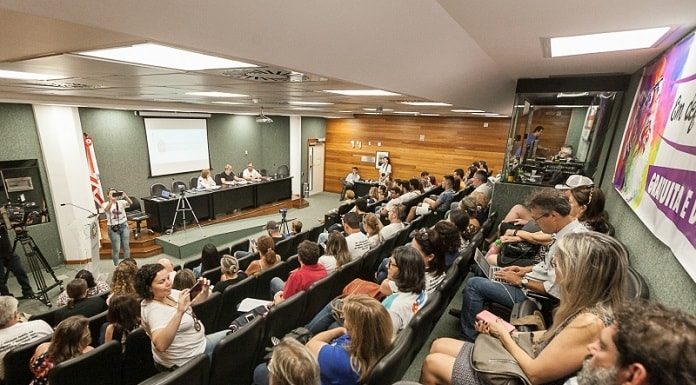 auditório da alesc lotado e com pessoas em bancada em palco à frente