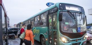 ônibus da empresa estrela parado ao lado de ponto onde há um homem e uma mulher em pé em um dia chuvoso