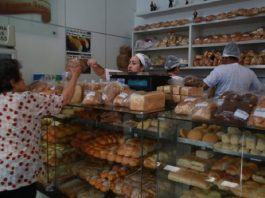 Santa Catarina tem saldo superior a 10 mil empregos em novembro padaria com atendente passando produto para cliente por cima do balcão cheio de pacotes de pão