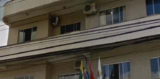fachada do prédio em que fica a câmara de biguaçu, onde há bandeiras do brasil, sc e do município na frente