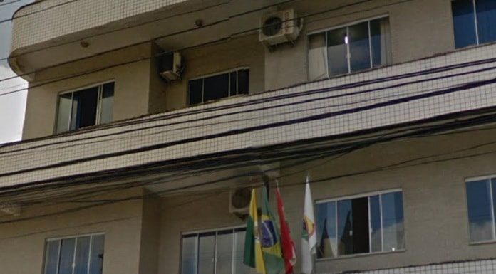 fachada do prédio em que fica a câmara de biguaçu, onde há bandeiras do brasil, sc e do município na frente