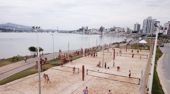 foto aérea das quadras de areia entre o mar e avenida, com pessoas usando e passendo em volta