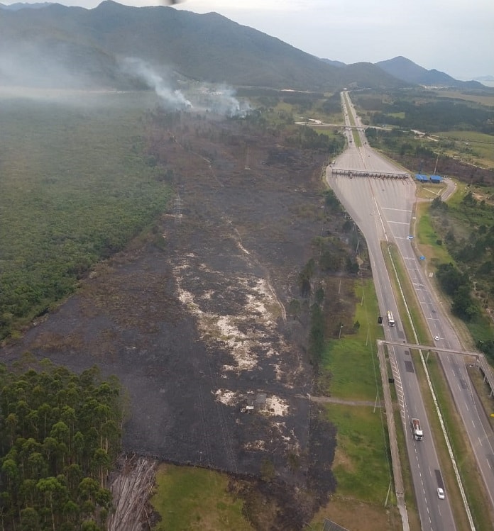 foto aérea da área queimada ao lado da rodovia com pedágio