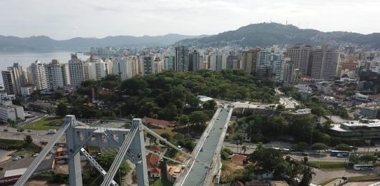 Eventos confirmados na programação de aniversário de Florianópolis ponte hercílio luz vista de cima em foto aérea e centro de florianópolis