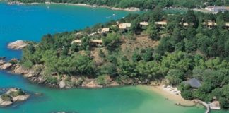Resort de luxo : foto aérea do costão com o resort cheio de árvores e ilha à frente em mar esverdeado com ligação por ponte