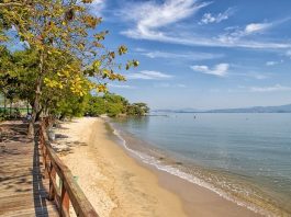 praia de sambaqui com mar parado em dia de sol, praia vazia e deck na orla