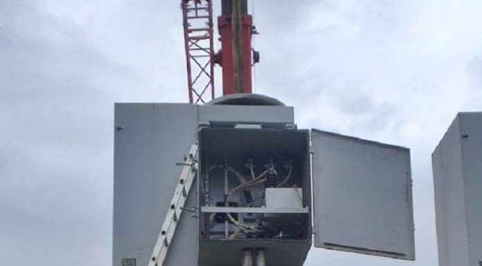 operários da casan ao lado de grande motor sobre uma estrutura de concreto