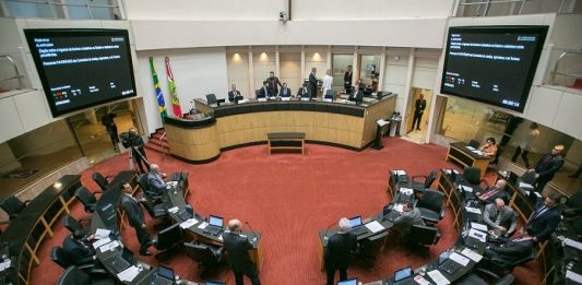 plenário da alesc visto de cima com as bancadas circulares ao centro e alguns deputados