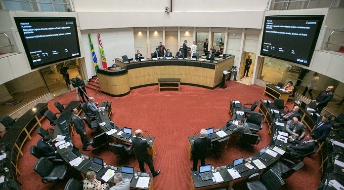 plenário da alesc visto de cima com as bancadas circulares ao centro e alguns deputados