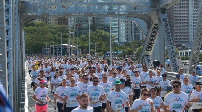 centenas de pessoas com mesma camiseta correndo sobre a pista da hercílio luz