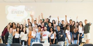 alunos e alunas em pé na frente da sala posam animados para a foto