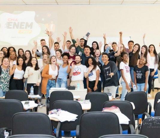alunos e alunas em pé na frente da sala posam animados para a foto