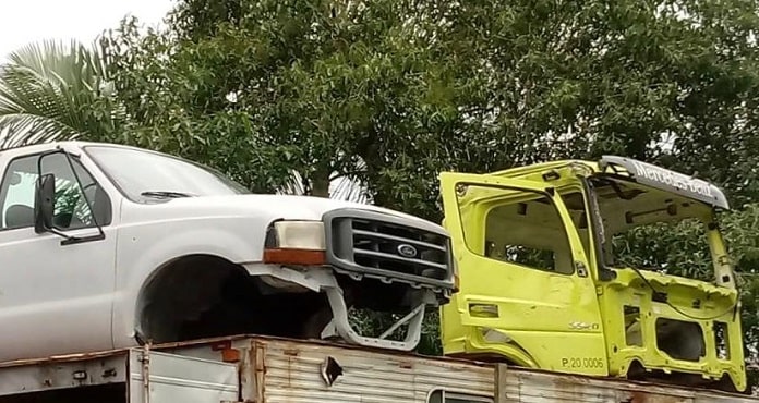 duas carrocerias de caminhonete e caminhão desmanchadas sobre outro caminhão
