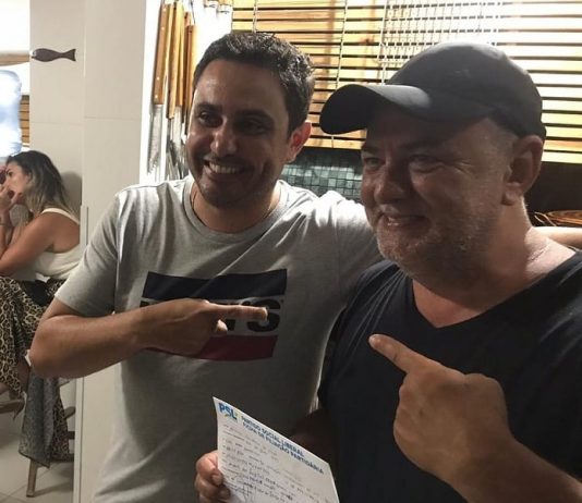 fernando anselmo e amauri dos projetos abraçados e sorridentes segurando ficha de filiação